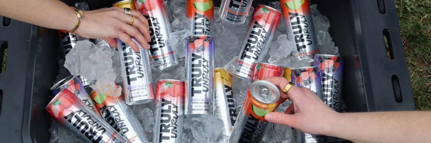 Des mains attrapant des canettes de Truly Hard Seltzer dans une glacière remplie de glace lors d'un concours Truly Canada